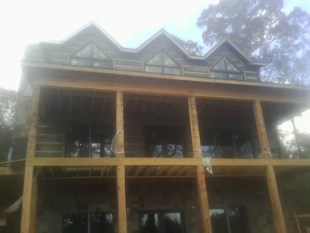 Dormers and porch framing on a large log home under construction — Roof Coating work by our crew in Montville
