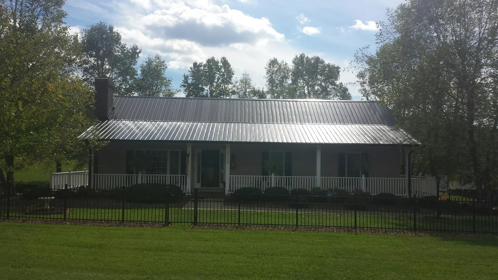 Gray metal roof on a brick ranch with a full width front porch — Gutter Guard Installation work by our crew in Montville